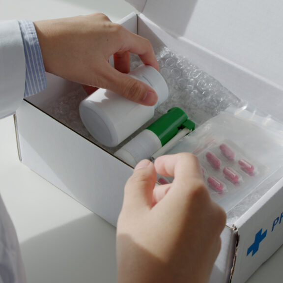 Close-up hand asia woman chemist help pack covid free first aid self recover care on desk give for customer people buy online clinic retail Rx drug store in telehealth telemedicine e-commerce order.